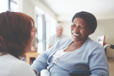Image shows a woman caring for an older person