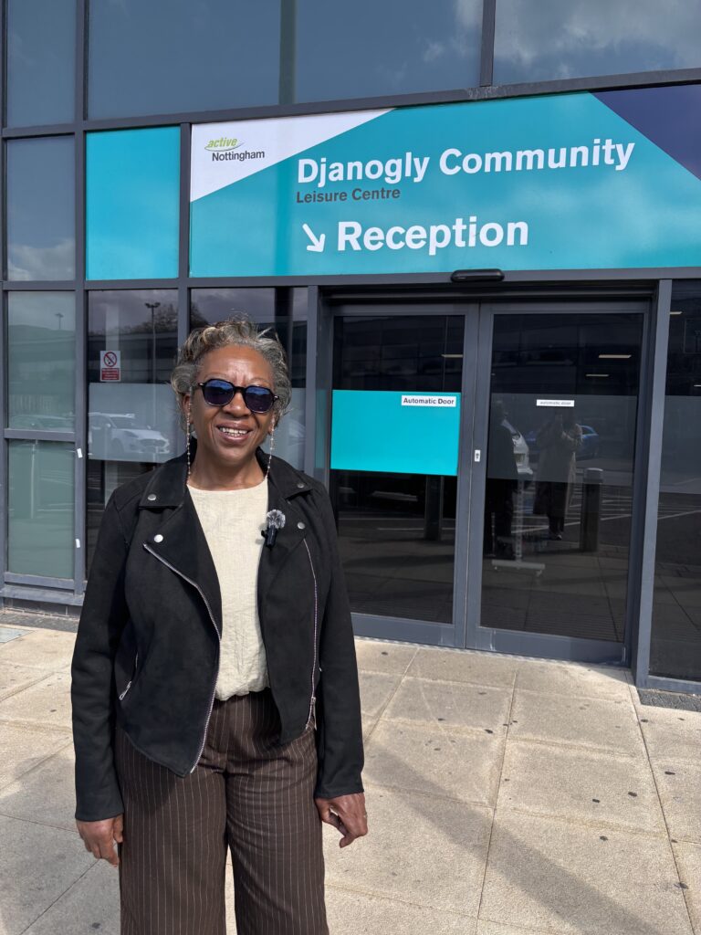 Cllr Jenkins standing outside the entrance of Djanogly Community Leisure Centre, with glass doors behind them and a large teal sign above reading “Djanogly Community Leisure Centre – Reception,” with the Active Nottingham logo.